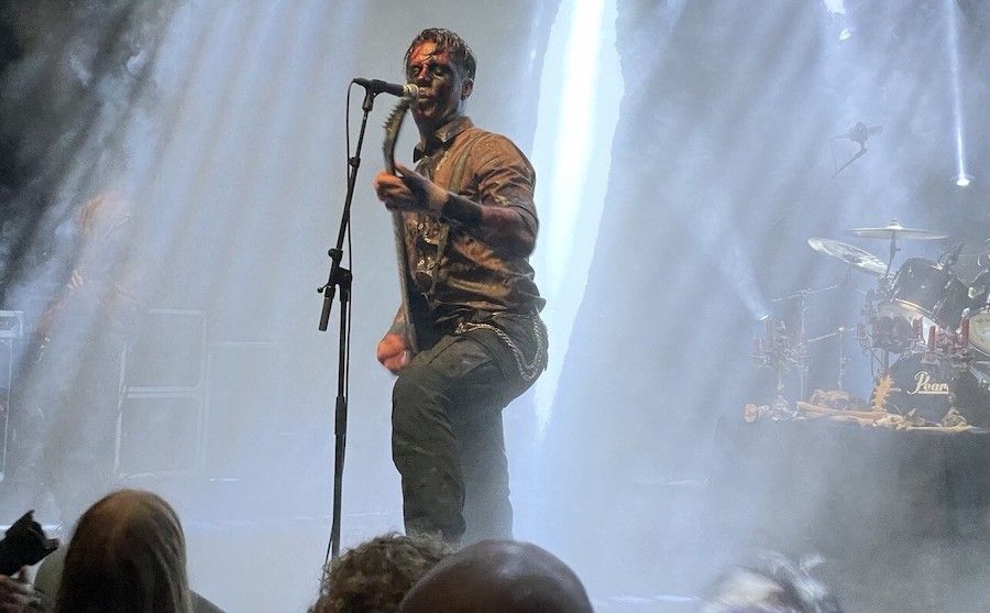 De zanger en tevens gitarist van Misþyrming op het podium. Hij ziet er uit alsof hij is ondergedompeld in een vat met teer.